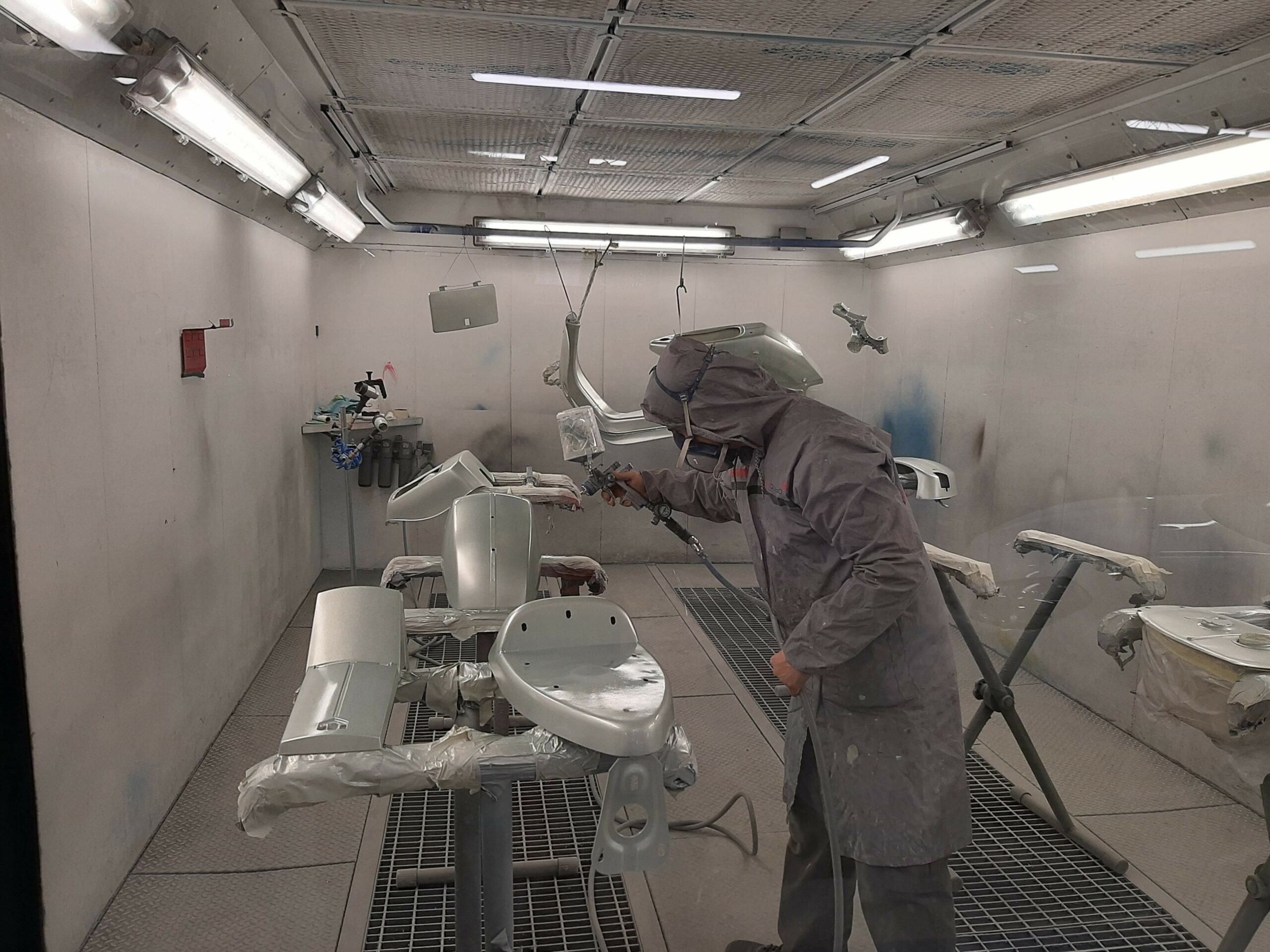 hombre pintando piezas en cabina