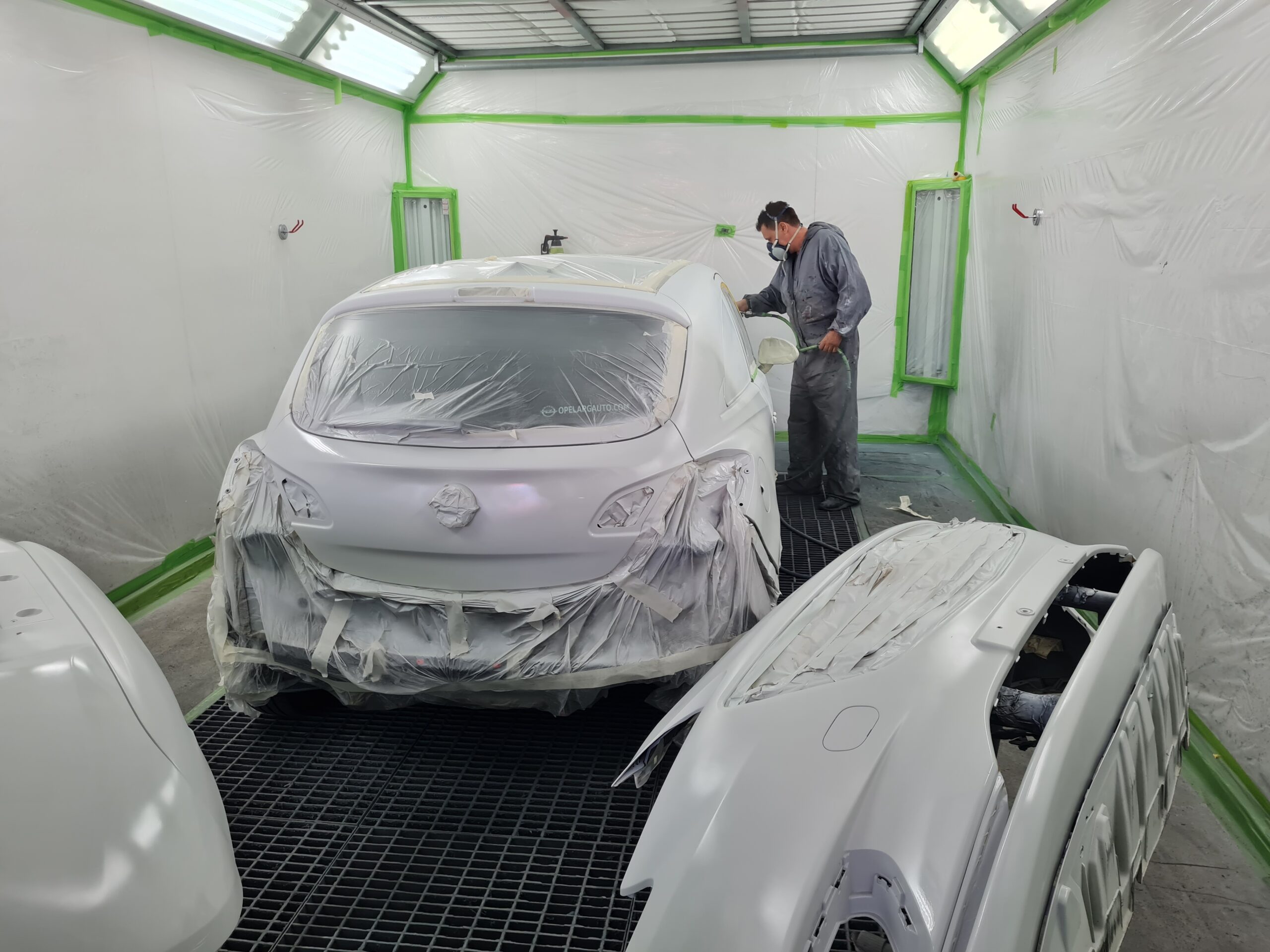 hombre pintando en cabina de pintura